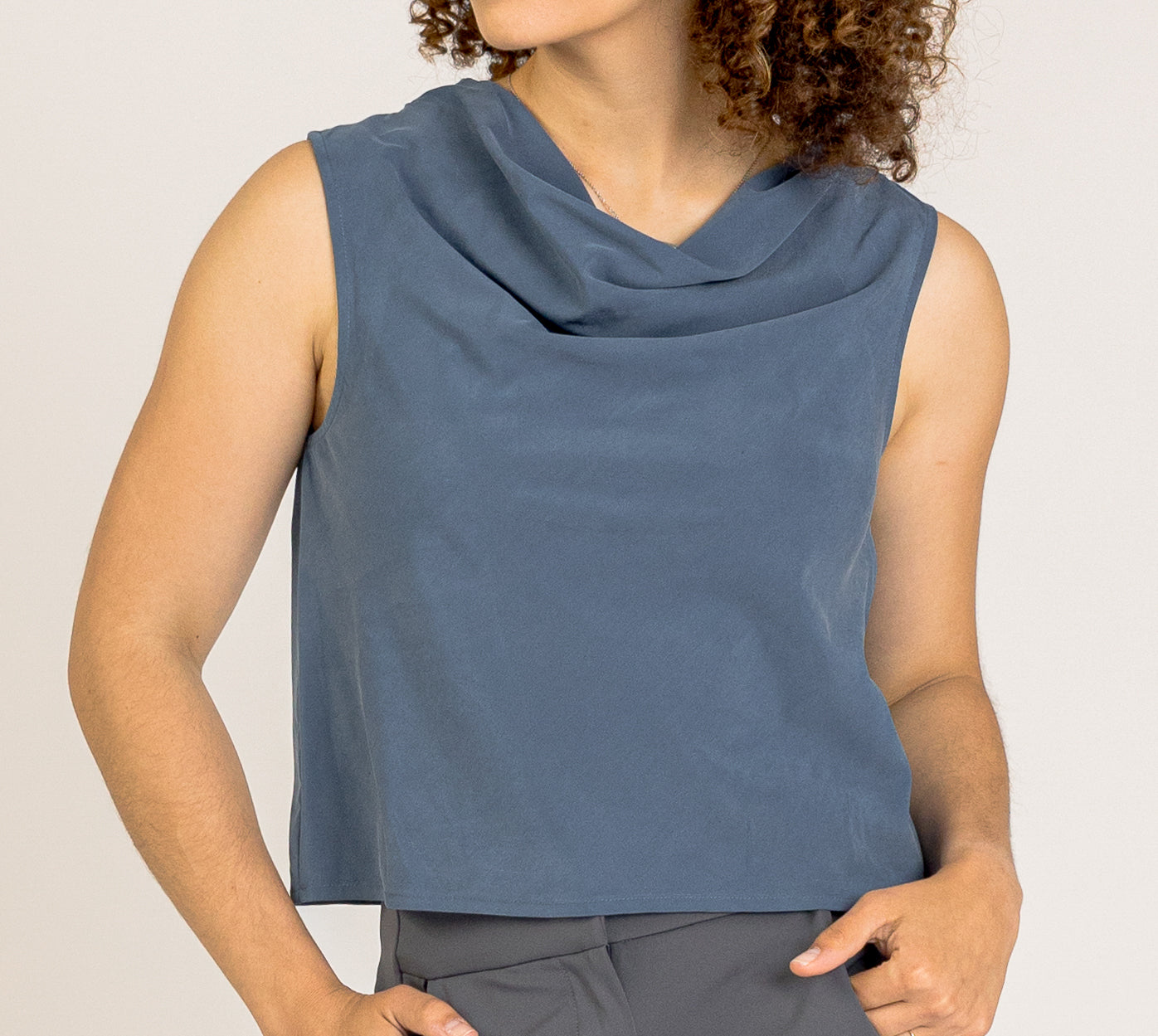 Jade Asymmetrical Cowl Top by SISU is a sleeveless top with a unique cowl neckline and an asymmetrical drape. It is crafted from soft, comfortable fabric and is perfect for business casual outfits.